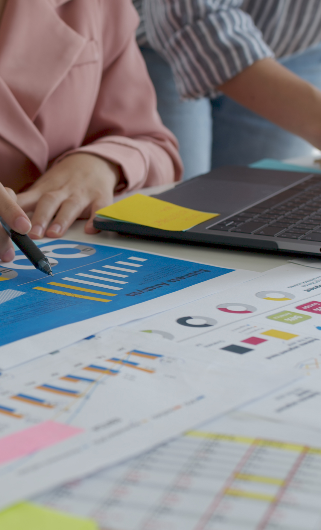 Deux personnes travaillent sur des graphiques et des données. - Agence web Prism